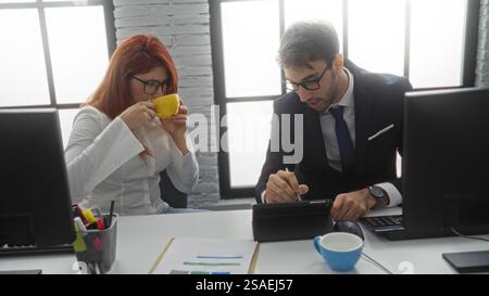 Man and woman working together in an office environment, highlighting business collaboration between two hispanic professionals in a corporate indoor Stock Photo