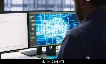 Machine learning expert in AI server room developing disaster recovery plans ensuring minimal downtime. Employee monitoring performance in artificial intelligence ran data center, camera A Stock Photo