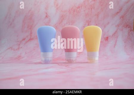 Set of three bottles of cosmetic products for cream, shower gel, shampoo, hair conditioner, on pink marble background. Stock Photo
