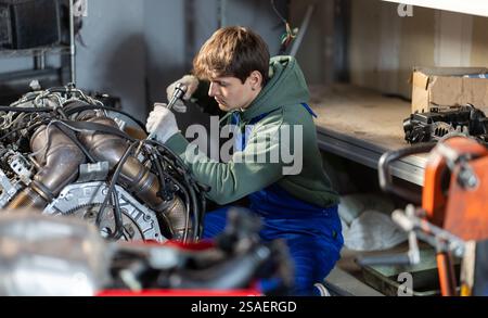 Young auto mechanic repairing an engine in garage Stock Photo