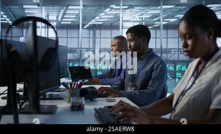 African american data center technicians implement AI predictive maintenance systems. Woman in server hub using artificial intelligence to identify hardware failures, camera A Stock Photo