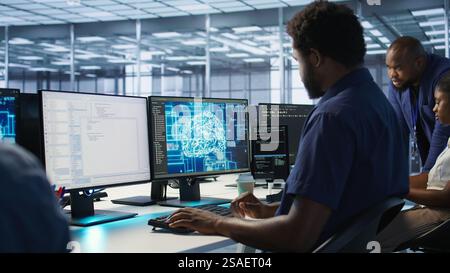 Machine learning expert in AI server room developing disaster recovery plans ensuring minimal downtime. Employee monitoring performance in artificial intelligence ran data center, camera A Stock Photo