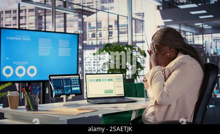 Black influential businesswoman evaluates company performance, using data reports and analytics to make informed decisions that optimize efficiency and productivity. Work ethic. Camera B. Stock Photo