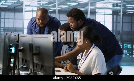 Teamworking engineers talking in server room, developing disaster recovery plans ensuring minimal downtime. Team of data center employees doing brainstorming, monitoring performance, camera A Stock Photo
