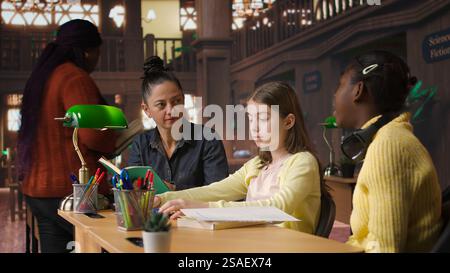 Female tutor mentoring schoolgirls in a school library setting ...