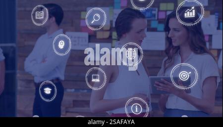 Digital icons image over businesswomen using tablet in modern office Stock Photo