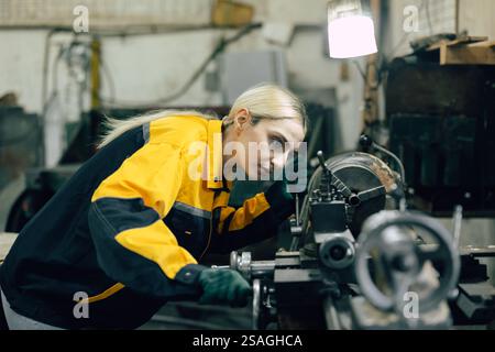 caucasian women worker working in heavy metal industry factory with steel part lathe machine Stock Photo