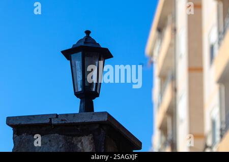 Small lamp lamp on a stone pillar. In the background a tree and blue sea. High quality photo. Stock Photo