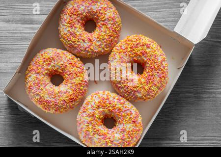 Iced ring doughnuts sprinkled with hundreds and thousands in a card box. Recycling eco friendly biodegradable packaging Stock Photo