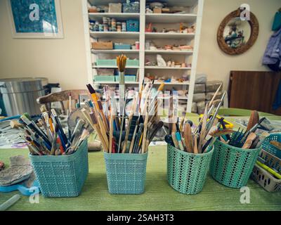 In the workshop of a ceramic artist. In the foreground on the table are special glasses with tools. Stacks, scallops, pencils and brushes. Stock Photo