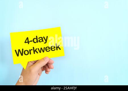 Human hand holding yellow speech bubble with written 4-day work week. Stock Photo