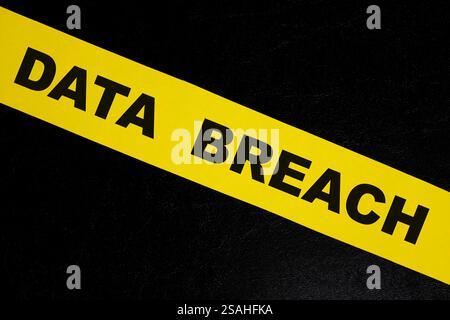 Data breach alert, caution and warning concept. Yellow barricade tape with word in dark black background. Stock Photo