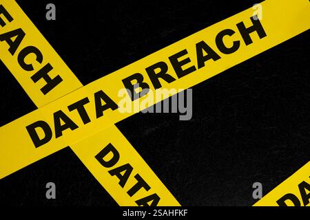 Data breach alert, caution and warning concept. Yellow barricade tape with word in dark black background. Stock Photo