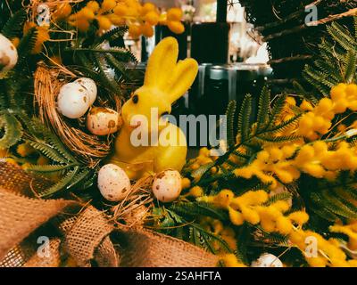 Easter decor with yellow bunny among branches and flowers in the spring season. Annual springtime holiday in April. Easter eggs and cute rabbit. Stock Photo