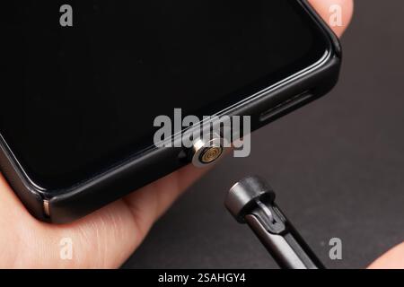 Connecting a magnetic cable to a smartphone for charging, close-up Stock Photo