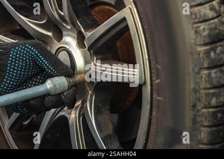Removing car mechanic to repair the leaky tire car wheels. Mechanic changing a car tire on a vehicle a hoist using an electric drill to loosen the bol Stock Photo