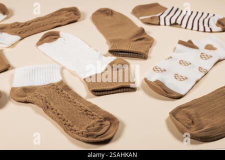 Multi-colored socks on a beige background. View from above. Many different socks for cold seasons. Socks are scattered on a bright background. Clothes Stock Photo