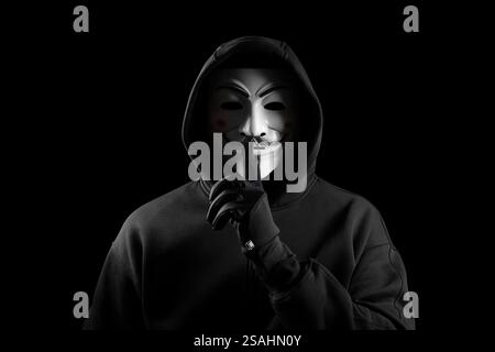 Dnipro. Ukraine 31 jan 2024: Man wearing vendetta mask in gloves with hoodie puts a finger to his lips showing a symbol of silence. This mask is symbo Stock Photo