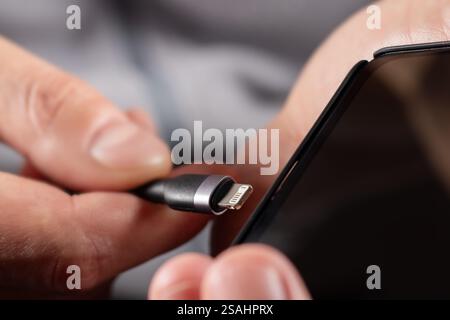 charging cables for phone in hand on gray background. Stock Photo