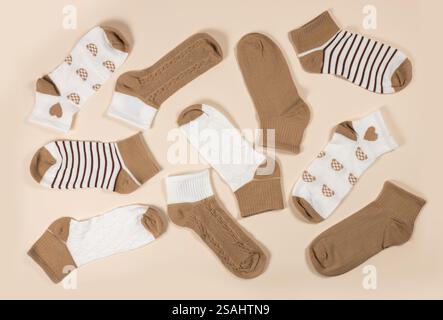 Multi-colored socks on a beige background. View from above. Many different socks for cold seasons. Socks are scattered on a bright background. Clothes Stock Photo