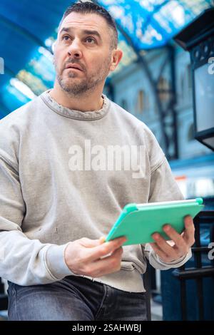 Focused Man Using Tablet While Waiting at Train Station looking at camera Stock Photo