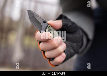 The man wearing tactical gloves using folding knife. Stock Photo