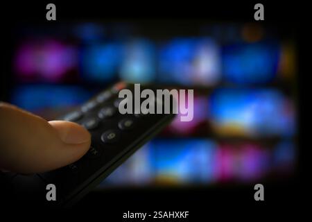 Tv online. Television streaming video. Media TV on demand. Online Multimedia video concept on TV set in dark room. Watching online TV with remote cont Stock Photo