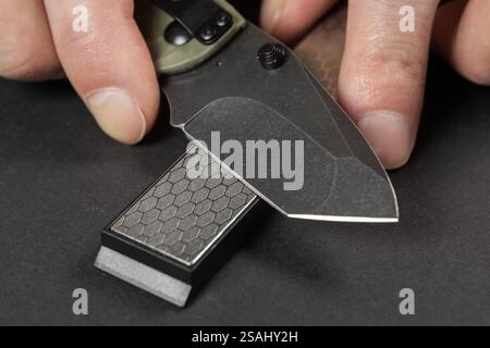 sharpening the knife with whetstone, close up. Stock Photo