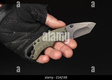 The man wearing tactical gloves using folding knife. Stock Photo