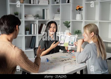 Team collaborating on UX UI presentation with prototypes and sketches. Stock Photo