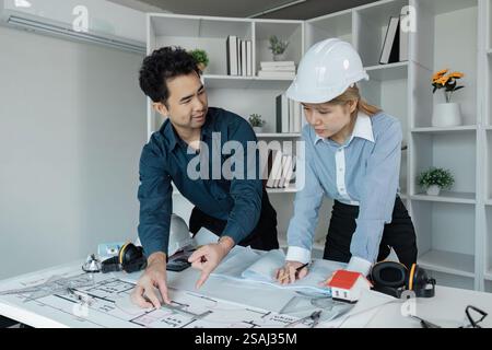 Diverse engineers collaborating on architectural blueprints in an office setting. Stock Photo