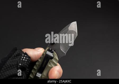 The man wearing tactical gloves using folding knife. Stock Photo