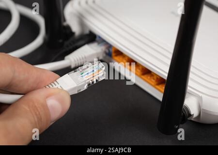 Man plugging internet cable into wi-fi router. Stock Photo