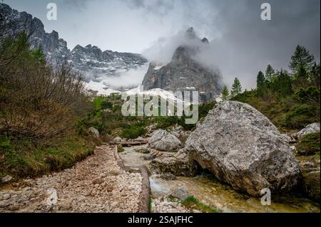 Rocky hiking trail near Lago Sorapis in the Dolomites (Dolomiti, Dolomiten), Italy. The path runs alongside a small mountain stream, with massive boul Stock Photo