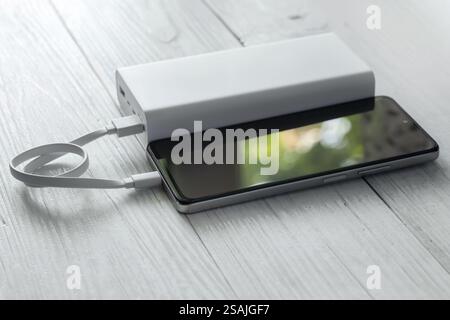 Charging power bank. Portable powerbank with white usb cable for charger mobile phone or smartphone battery. Stock Photo