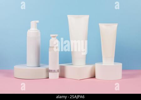 Cosmetics for skin . Different types of cosmetic containers placed on podium against a blue and pink background. Dispenser and tubes. Skincare or beau Stock Photo