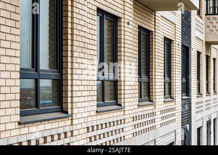 Exterior facade of a beige brick building featuring large dark-framed windows, captured in natural daylight, urban architecture Stock Photo