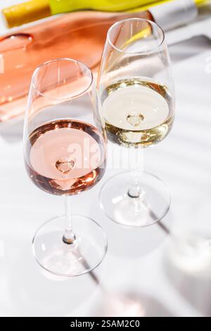 Two wine glasses filled with rose and white wine, standing gracefully on a bright, minimalist background. A vibrant display of wine's variety and eleg Stock Photo