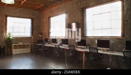 Empty Interior Of Modern Open Plan Design Office With Row Of Computers On Desk Stock Photo