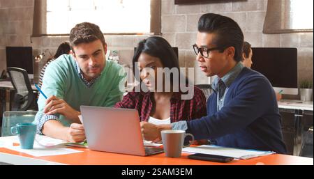 Three Designers In Creative Business Using Laptop Meeting In Modern Multi-Cultural Office Stock Photo