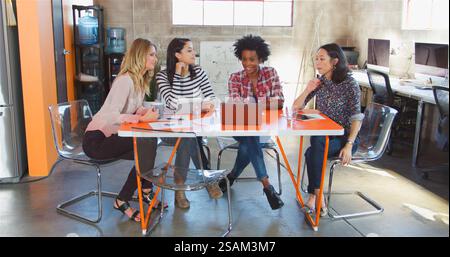 Group Of Female Designers Around Table Having Meeting In Creative Modern Office Stock Photo
