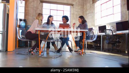 Group Of Female Designers Around Table Having Meeting In Creative Modern Office Stock Photo