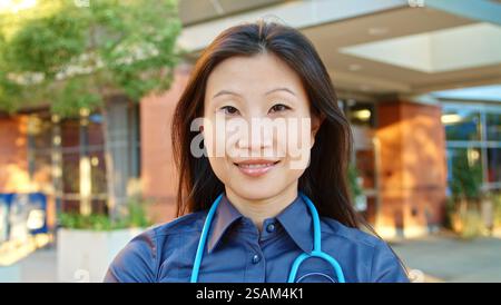 Portrait Of Female Doctor With Stethoscope At Work Standing Outside Modern Hospital Stock Photo