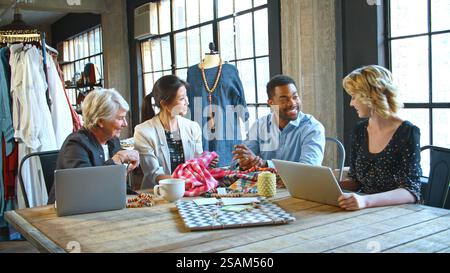 Male And Female Fashion Designers In Studio Meeting Discussing Fabric Swatches Stock Photo