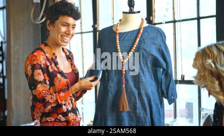 Close Up Of Female Fashion Designer In Studio Meeting With Colleagues Discussing Garment On Dummy Stock Photo