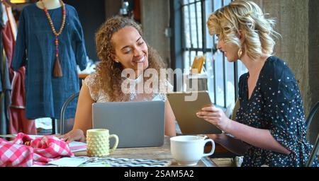 Two Female Fashion Designers In Studio Meeting Working On Laptop Together Stock Photo