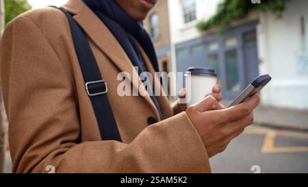 Close Up Of Man With Takeaway Coffee Checking Messages Or Social Media On Street Using Mobile Phone Stock Photo