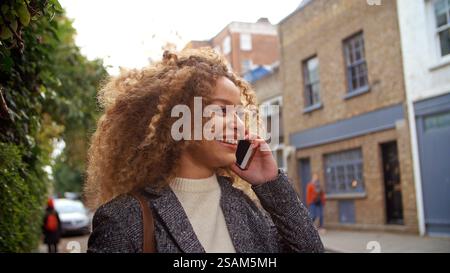 Close Up Of Stylish Young Woman Making Call Using Mobile Phone On City Street Stock Photo