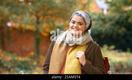 Portrait Of Smiling Young British Muslim Woman Wearing Headscarf In Autumn Park Stock Photo