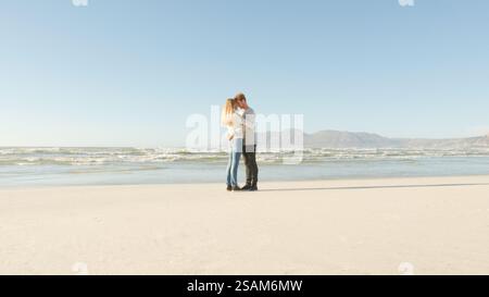 Loving Couple On Vacation Face To Face Standing On Winter Beach Hugging Stock Photo